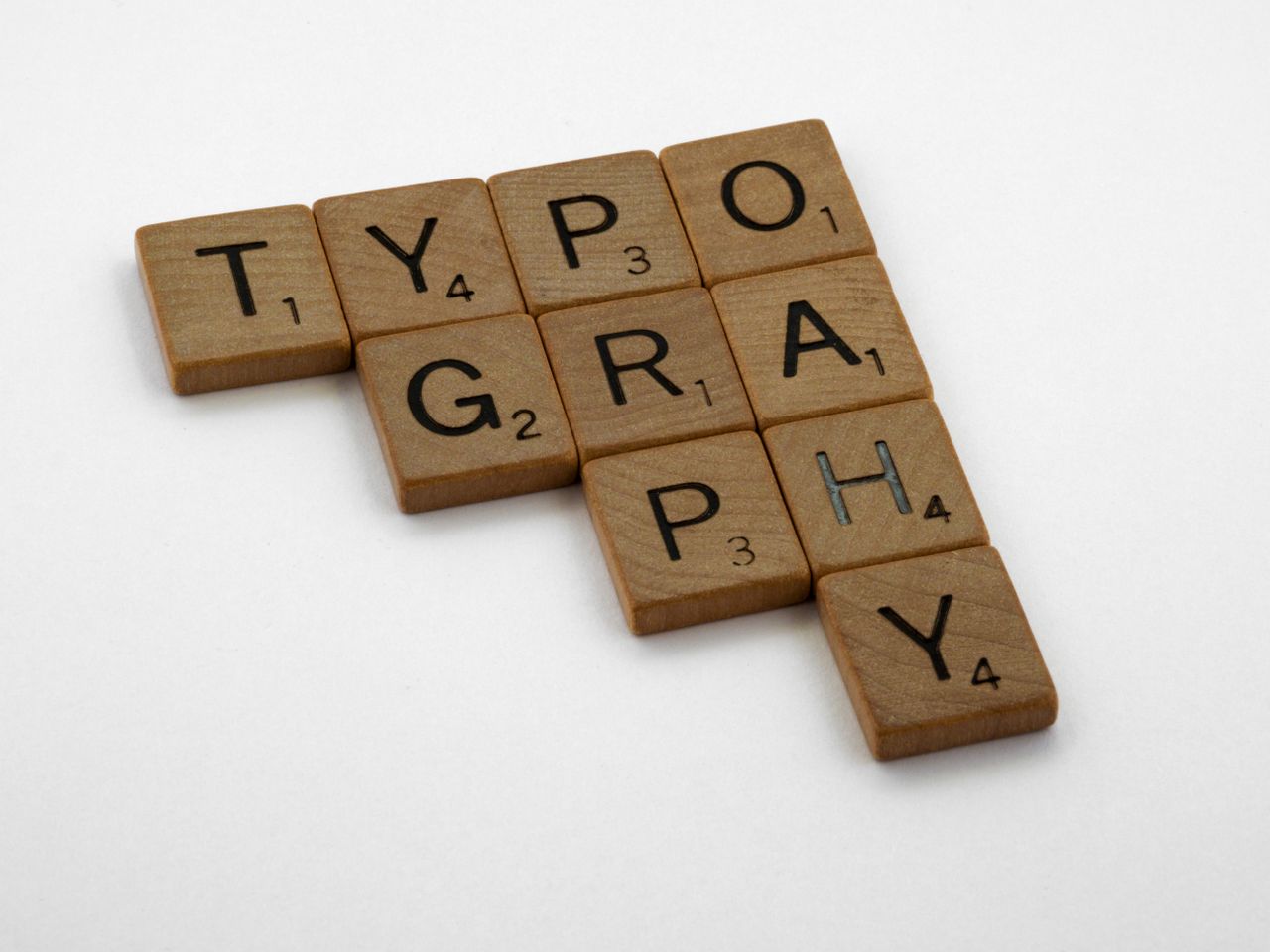 Offerings Scrabble tiles spelling 'Typography' on a white background for creative design concepts.