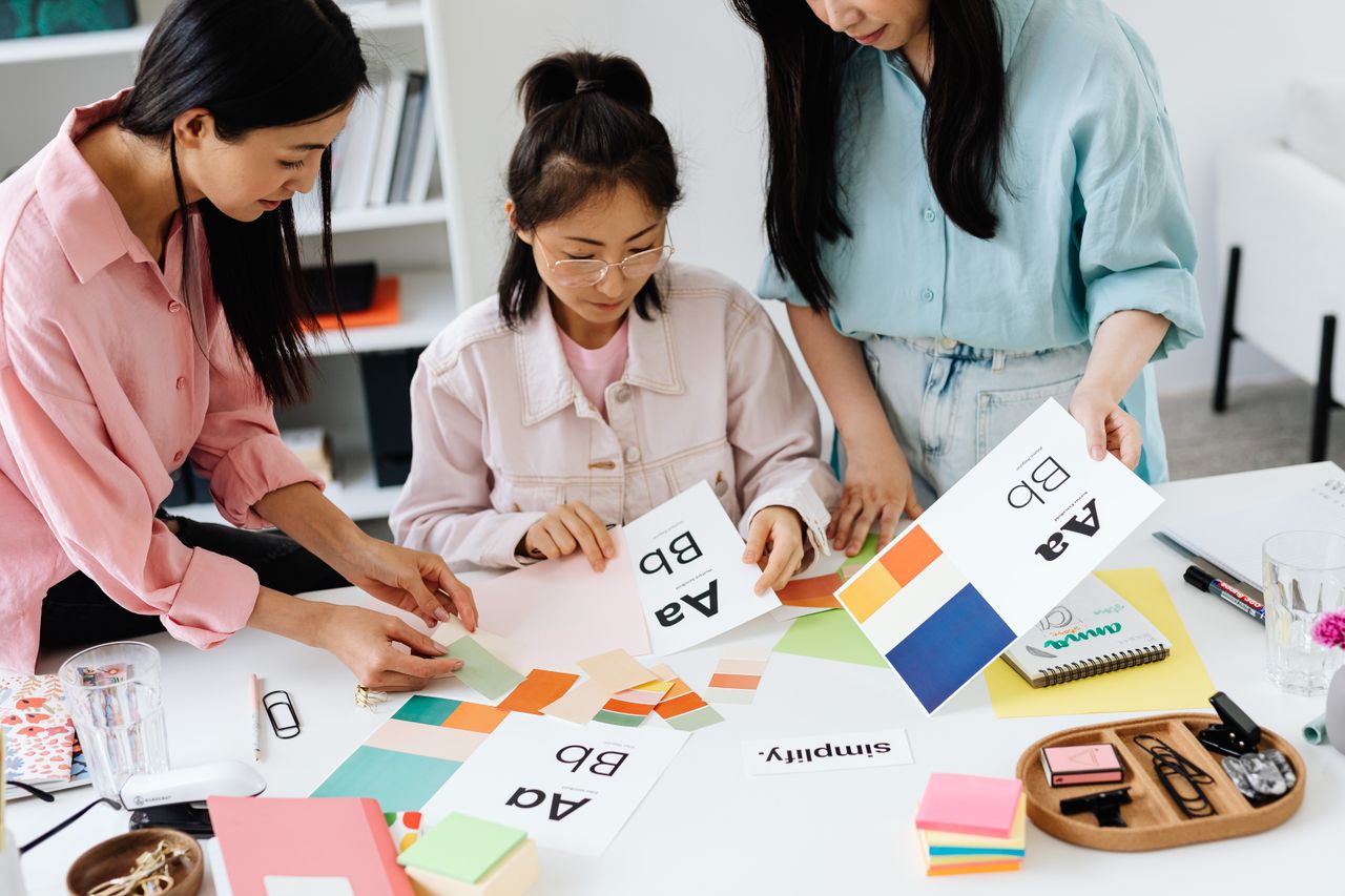 Offerings Three women engage in teamwork on a design project, sharing ideas and creativity.